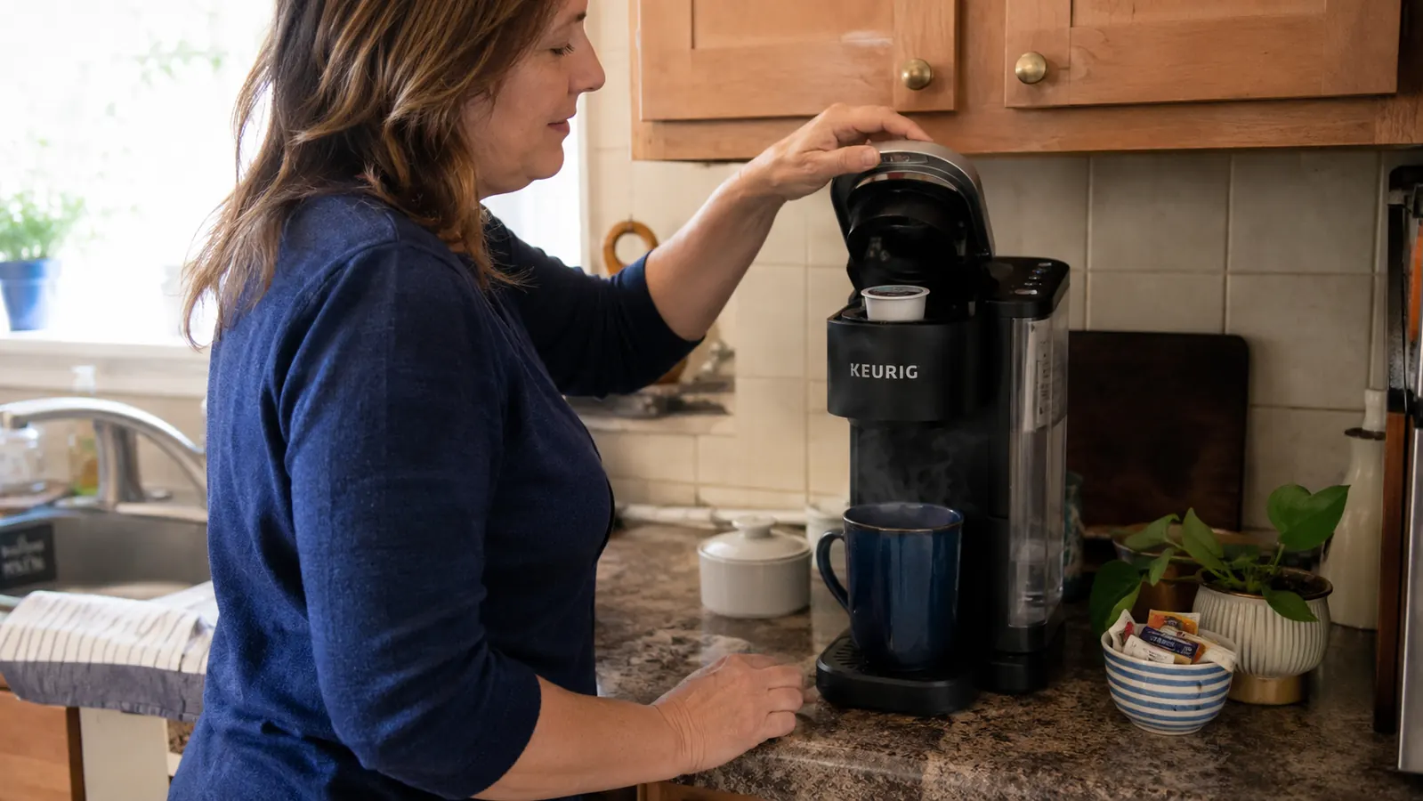 Hand lifting the top of the Keurig K-Express to load a K-Cup pod before brewing