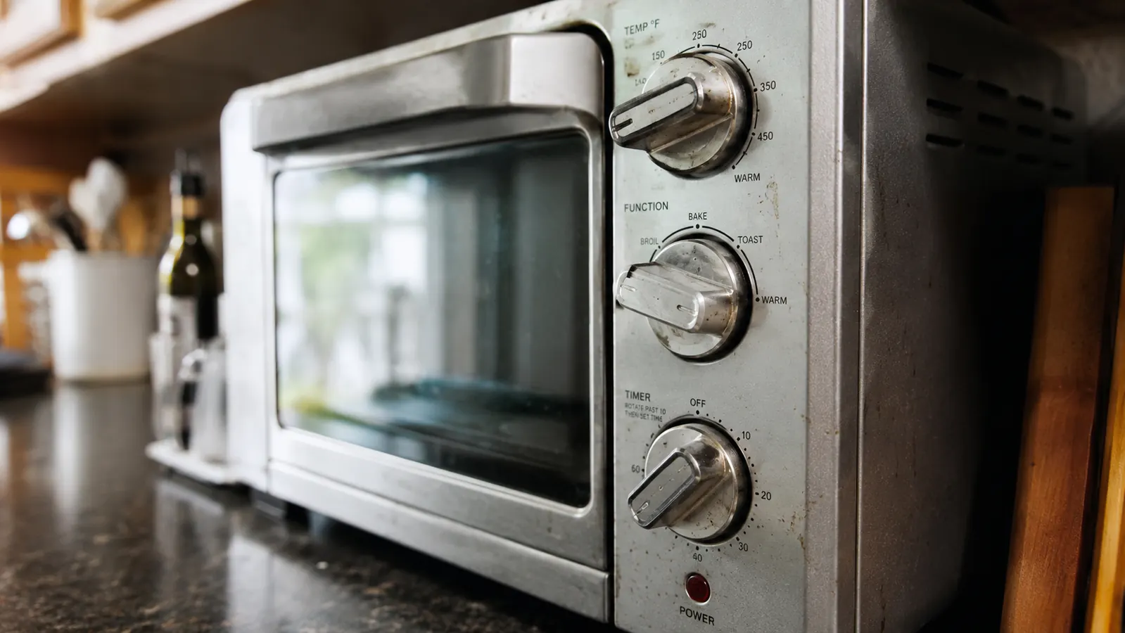 Close-up of the mechanical timer dial and toast shade knob on the front of the toaster oven