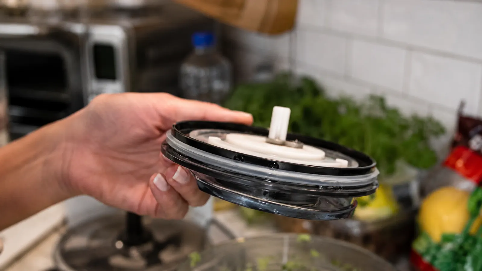 Close-up of the chopper's clear lid and rubber gasket showing a thin gap where liquid has started to seep during pressing