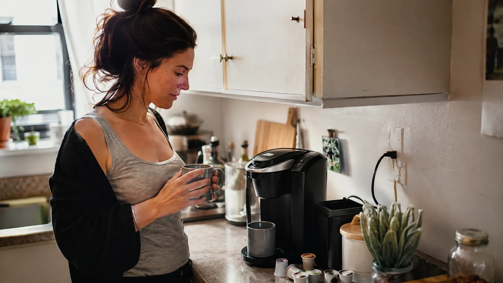 Keurig K-Express single-serve coffee maker on a narrow apartment counter with a small stack of loose K-Cup pods beside it